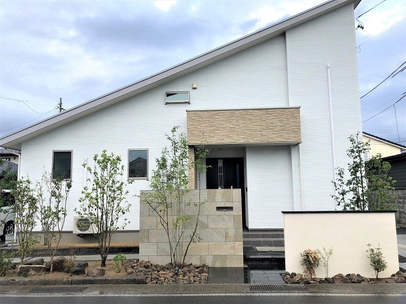 タイル張りの門袖と雑木のファサード。