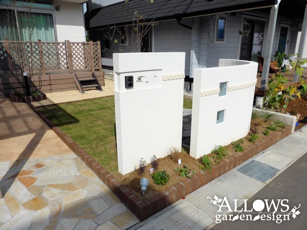 曲線形状の塗り壁で道路と仕切ったガーデン