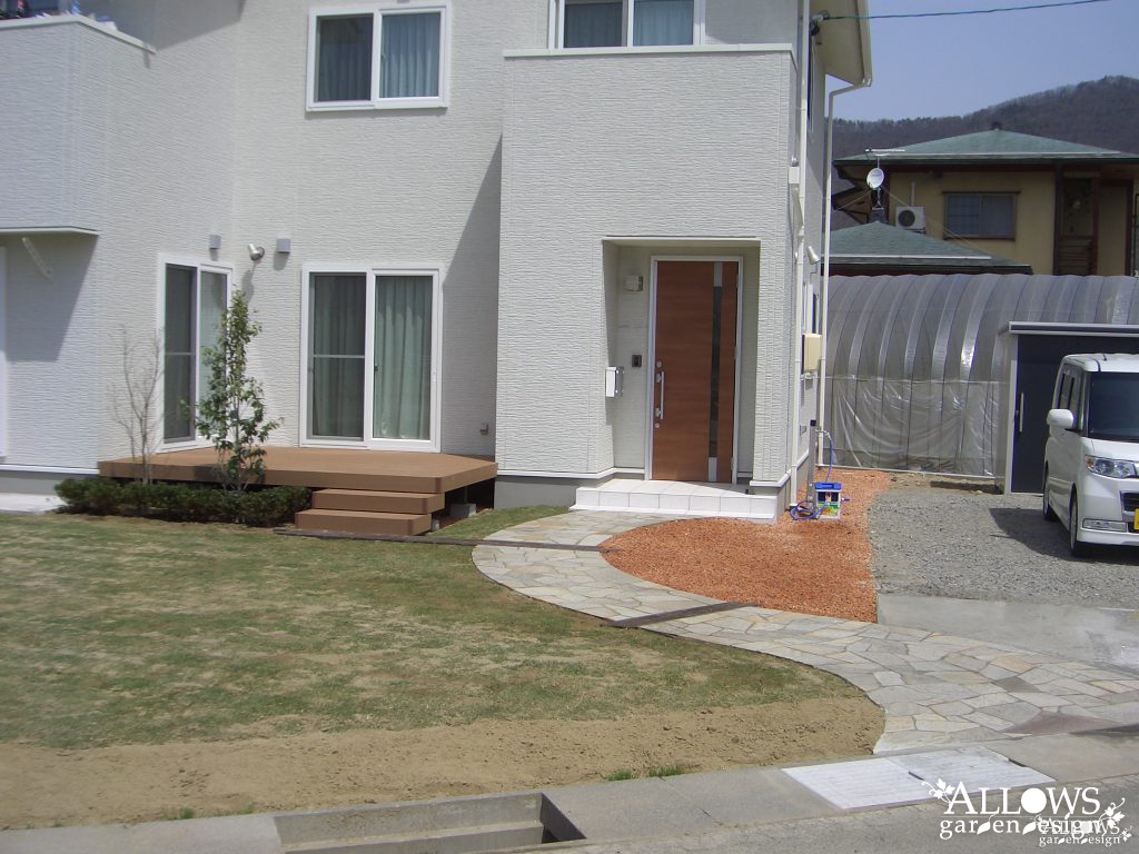 広い芝生の庭と綺麗な曲線の石張りアプローチ